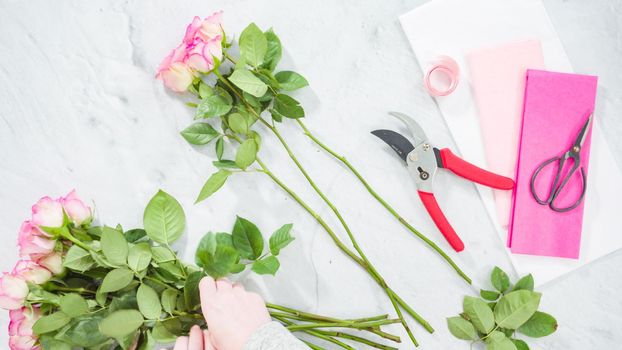 Flat lay. Step by step. Florist arranging a bouquet from pink roses.