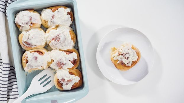 Flat lay. Glazing freshly baked cinnamon rolls in a blue baking pan.