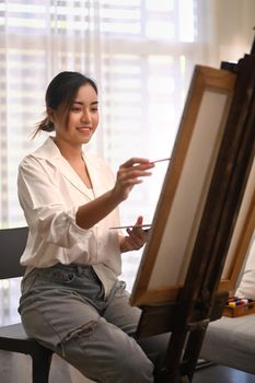 Positive woman painting picture with watercolor at cozy home. Art, creative hobby and leisure activity concept.