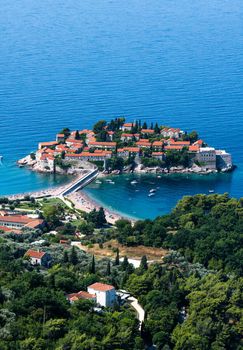 Beautiful Sveti Stefan island in Montenegro and forest from above. Scenic view on adriatic sea and luxury resort on mediterranean coast with mountains