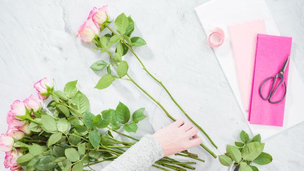 Flat lay. Step by step. Florist arranging a bouquet from pink roses.