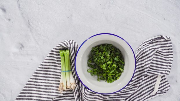 Flat lay. Step by step. Chopping organic green onions on a wood cutting board.