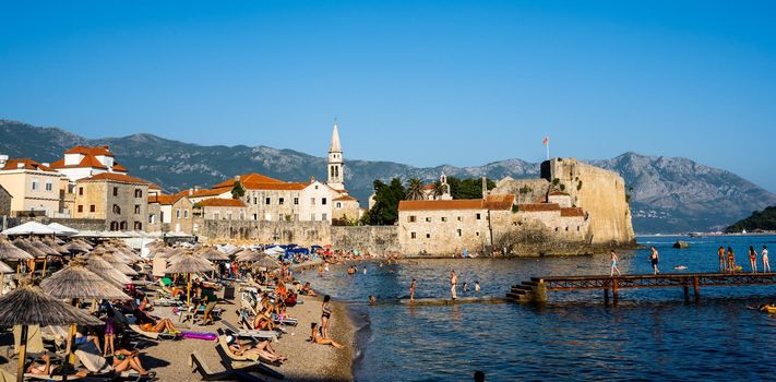 Budva, Montenegro - 30 July 2021: Ancient Budva in Montenegro scenic view from adriatic sea. Old mediterranean architecture with orange roofs