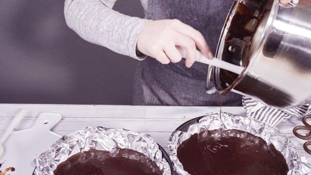 Step by step. Pouring melted batter into baking pans lined with cooking foil to make simple chocolate fudge.