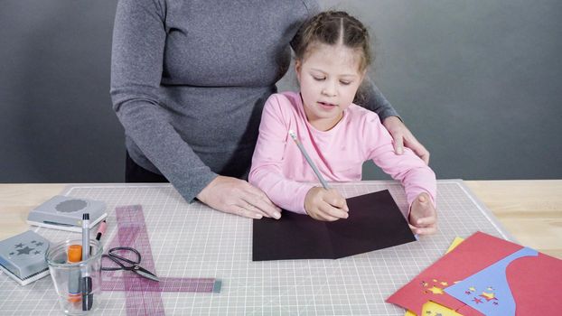 Little girl making a handmade Father's Day card from construction paper.