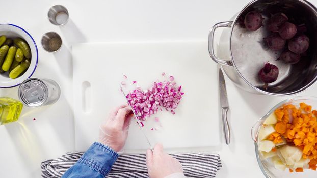 Flat lay. Step by step. Cutting cookies vegetables on a white cutting board for vinaigrette salad.