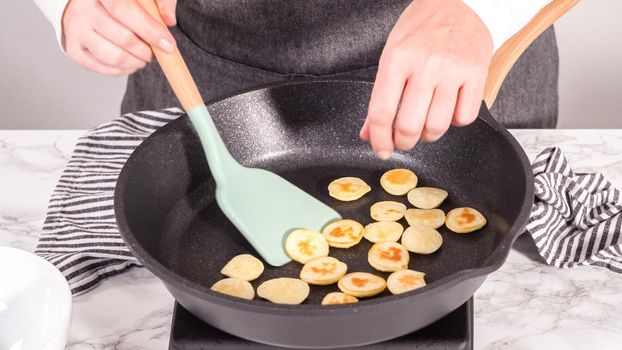 Step by step. Frying mini pancake cereal in a nonstick frying pan.