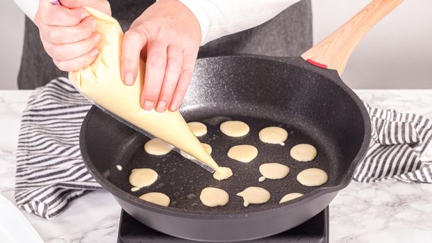 Step by step. Frying mini pancake cereal in a nonstick frying pan.