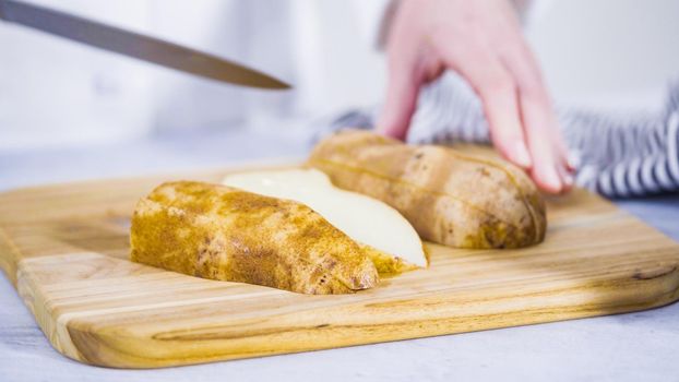 Step by step. Slicing russet potatoes in wedges with olive oil and spices to bake in the oven.