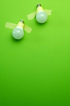 Two lamps lightbulb attached with tape on green background. Concept of creativity and team inspiration