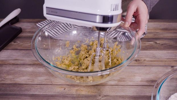 Step by step. Mixing ingredients to bake oatmeal raising cookies in a glass mixing bowl.