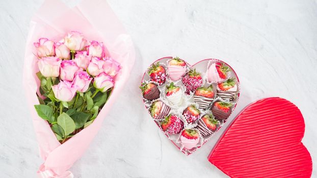 Flat lay. Step by step. Bouquet of pink roses with a box of chocolate dipped strawberries.