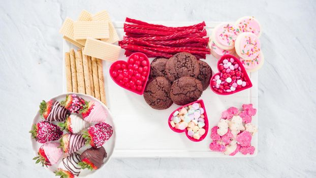 Flat lay. Step by step. Cheese board with candies and cookies for Valentines Day.