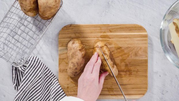 Flat lay. Step by step. Slicing russet potatoes in wedges with olive oil and spices to bake in the oven.