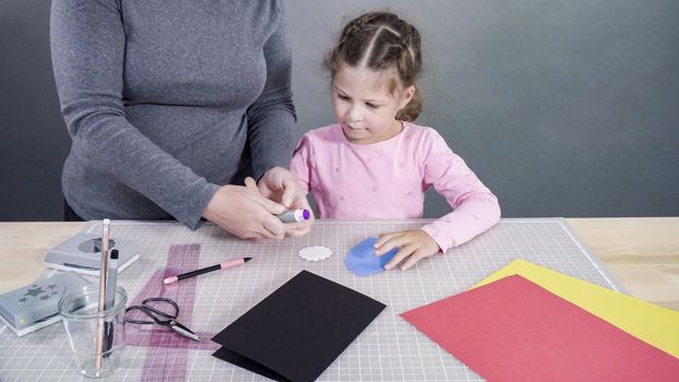 Little girl making a handmade Father's Day card from construction paper.