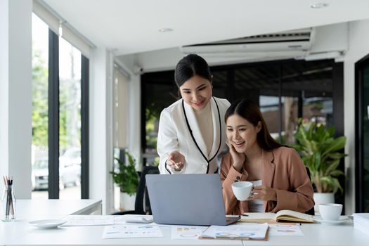 Two asian business partnership coworkers discussing a financial planning graph and company during a budget meeting in office room