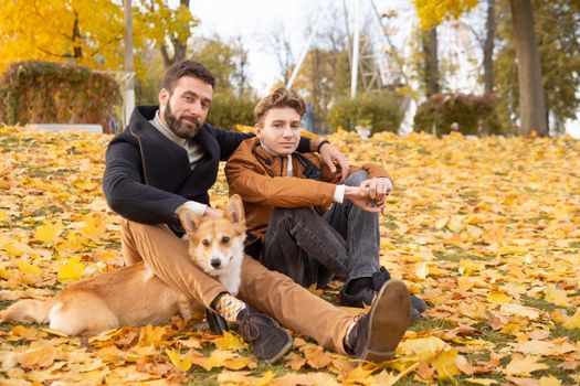 Father and son with a pet on a walk in the autumn park.