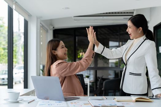 businesswomen giving hi five touching hands and thumb up during meeting for celebration business achievement and success with teamwork.