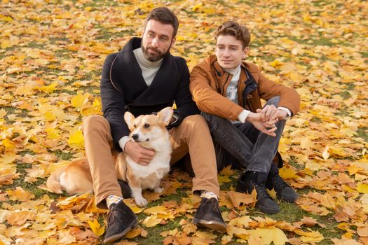 Father and son with a pet on a walk in the autumn park.