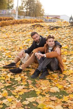 Father and son with a pet on a walk in the autumn park.