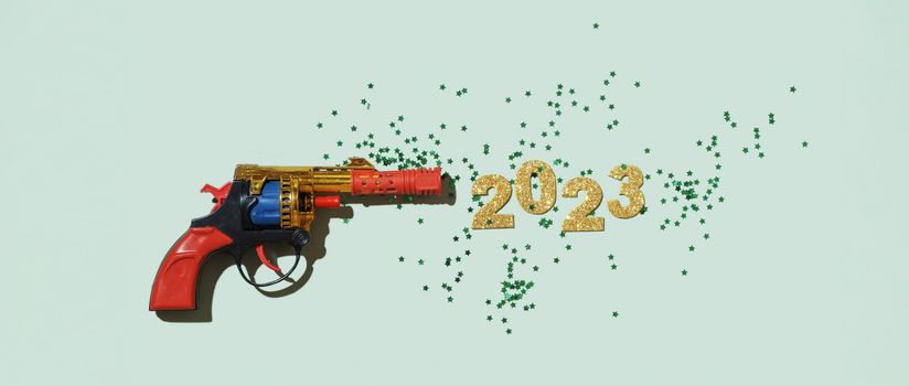 Creative composition with a toy gun and numbers of the new year 2023.