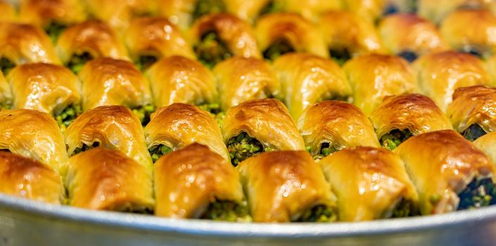 Baked pistachio baklava texture on metal plate.