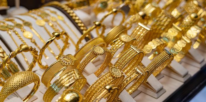 Golden luxury bracelets on stand in jewelry shop.