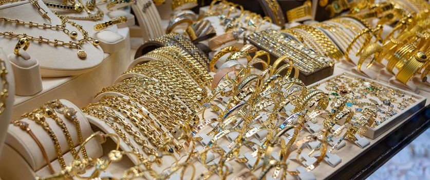 Many golden bracelets on stand in jewelry close up.