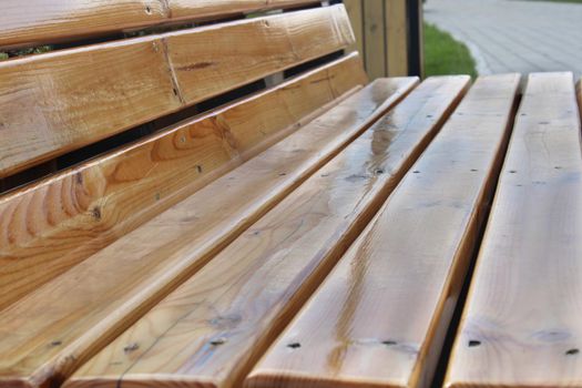 Light wooden bench in the city park close-up. Urban architecture.