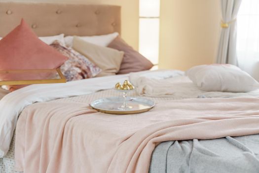 Bedroom interior in light colors with wooden furniture and pillows. Lamps on both sides