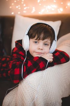 A boy with headphones is lying on the sofa lifestyle. The boy listens to music. New Year's mood.