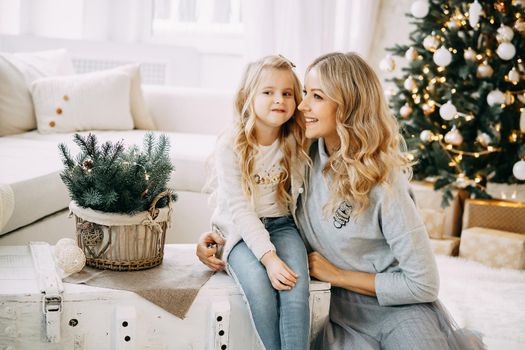 Happy family: mother and daughter. Family in a bright New Year's interior with a Christmas tree.