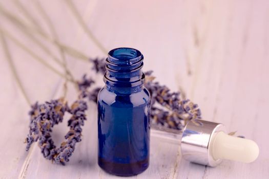 blue bottle of lavender massage oil on lavender wooden background