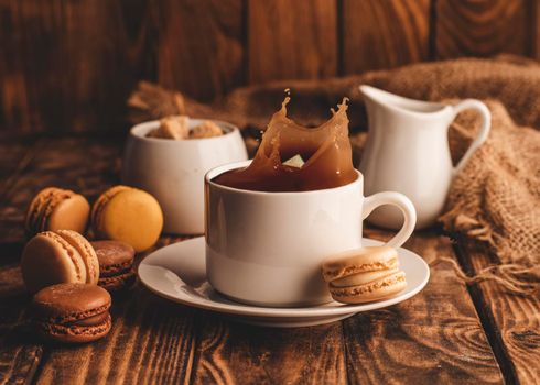 cup of black offee, milk, sugar and macaroons on wooden background