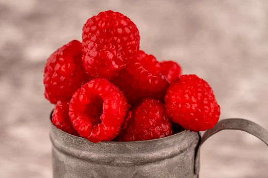 fresh raspberry berries in a cup on brown background