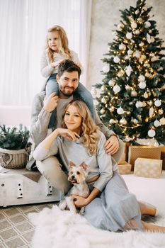 Happy family: mom, dad and pet. Family in a bright New Year's interior with a Christmas tree.