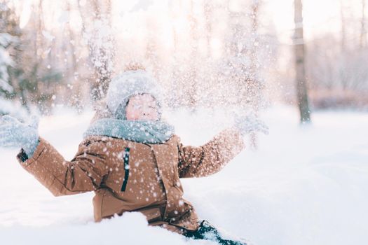 The boy throws snow in winter lifestyle . Winter walks. An article about children's winter leisure. Entertainments