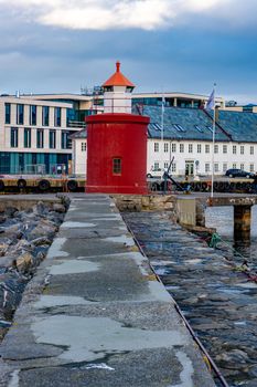 A beautiful vertical shot of a red lighthouse in the Alesund port town, Norway; sky background