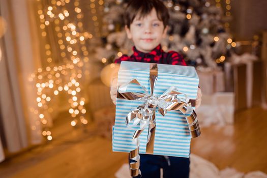 A boy with a New Year's gift under the tree lifestyle. New Year and Christmas. Festive decoration. New Year's gift