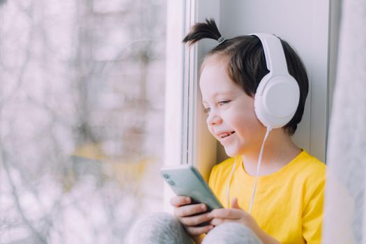 A boy with a phone is sitting on a lifestyle window . Social media. Modern children. An article about developed children. Modern technologies