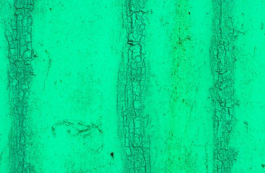 Abstract background of an old time-damaged concrete wall covered with old green paint with smudges and stains.