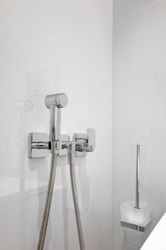 Close-up of chromium bidet shower in a toilet. Vertical shot of clean and new spray shower