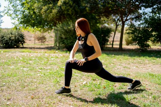 Full body female athlete in activewear lunging on grassy lawn during fitness workout on sunny summer day in park