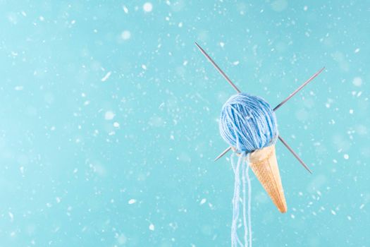 waffle cone with pink yarn instead of ice cream hobby concept on blue snowing background making your own presents Space for text
