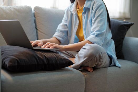 Close up of women working and studying using laptop at home. Women working, studying, researching using laptop while sitting on couch at home. Close up. Education and online learning concept.