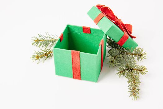 Present. Gift box with a bow. New Year's surprise. Red and green box with a gift. On a white background, top view. Close-up. Tied with a beautiful ribbon for gifting. Under the tree.
