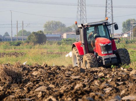 farmer with tractor plowing the land in the countryside.