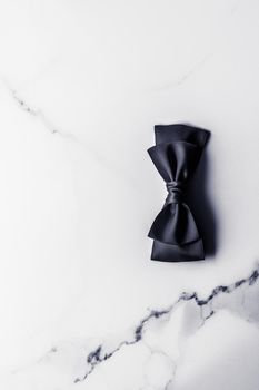Holiday gift, decoration and sale promotion concept - Black silk ribbon and bow on marble background, flatlay