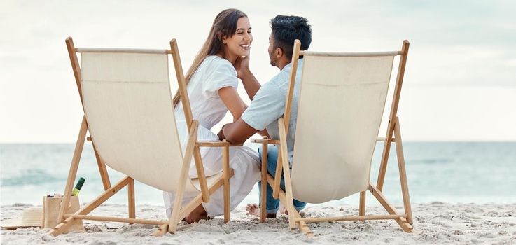 Happy, travel and love of a couple from India on a beach, ocean and sea vacation. Happiness of Indian people smile with a peace, relax and calm mindset together by the waves, sand and water in nature.