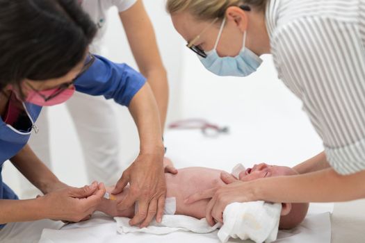 Baby beeing vaccinated by pediatrician in presence of his mother. Preventive vaccination against Diphtheria, whooping cough, tetanus, hepatitis, haemophilus influenzae, pneumococcus, poliomyelitis.